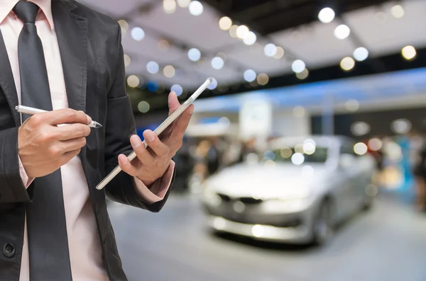 Homme d'affaires en utilisant la tablette sur la photo floue abstraite de fond de l'exposition automobile, ton de couleur bleue — Photo