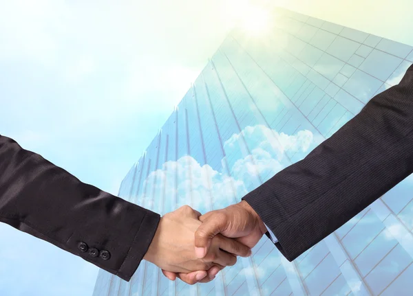 Sacudir de mão entre um homem de negócios no edifício de vidro moderno com fundo em nuvem, conceito de negócio — Fotografia de Stock
