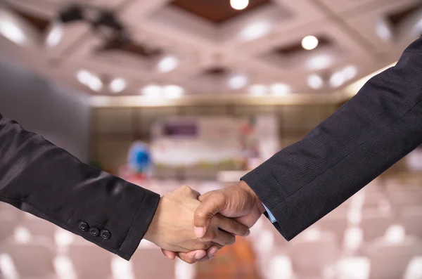 Hand shake between a businessman and a businesswoman o Abstract blurred photo of Meeting preparation at bright conference hall — Stock Photo, Image