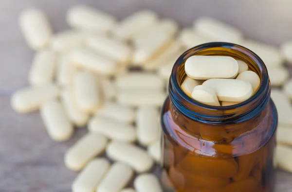 Píldoras o vitaminas en frascos de medicina sobre fondo de madera — Foto de Stock