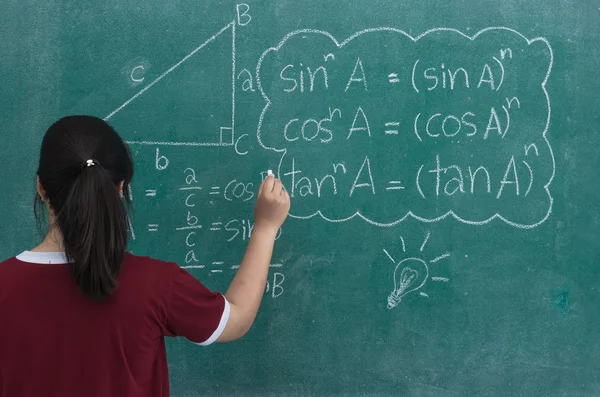 Chica joven está escribiendo las fórmulas matemáticas en una pizarra — Foto de Stock