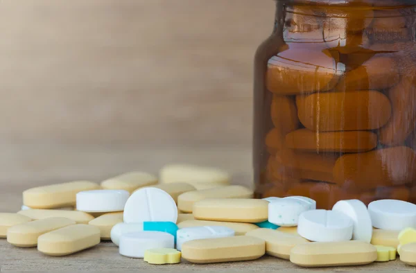 Muchas píldoras y vitaminas en botellas de medicina sobre fondo de madera — Foto de Stock