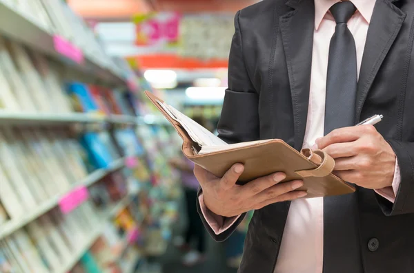 Businessman writing the note book on Abstract blurred photo of book store background