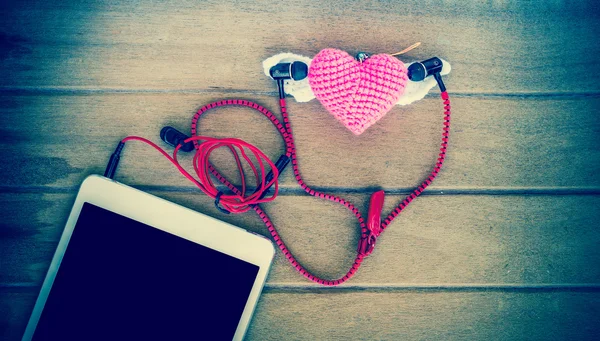 Fones de ouvido de áudio portáteis com tablets e coração Crochê sobre fundo de madeira, cor vintage — Fotografia de Stock