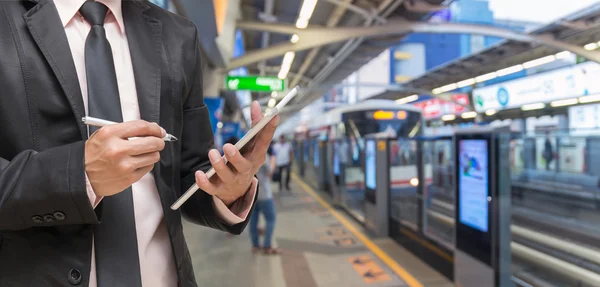 Empresário usando o tablet na foto embaçada abstrato da estação ferroviária céu com as pessoas de fundo — Fotografia de Stock