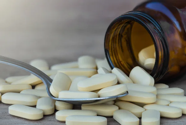 Hap ya da vitamin kaşık arka plan üzerinde tıp şişelerde — Stok fotoğraf
