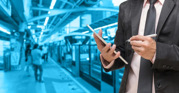 Бизнесмен, использующий планшет на Абстрактном размытом фото с неба вокзал с людьми фон, синий тон цвета — стоковое фото