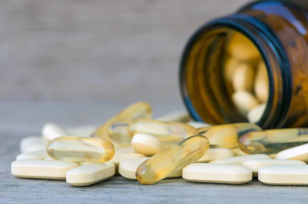 Pillen of vitamine in geneeskundeflessen op houten achtergrond — Stockfoto