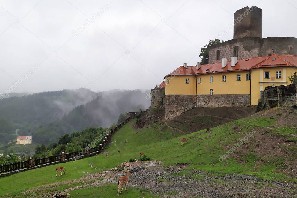 Gothic castle Svojanov in Bohemia on a rainy day. It was founded around 1224 and is one of the oldest stone castles in Bohemia. The new extension is from the last century. Below is the church from 1786