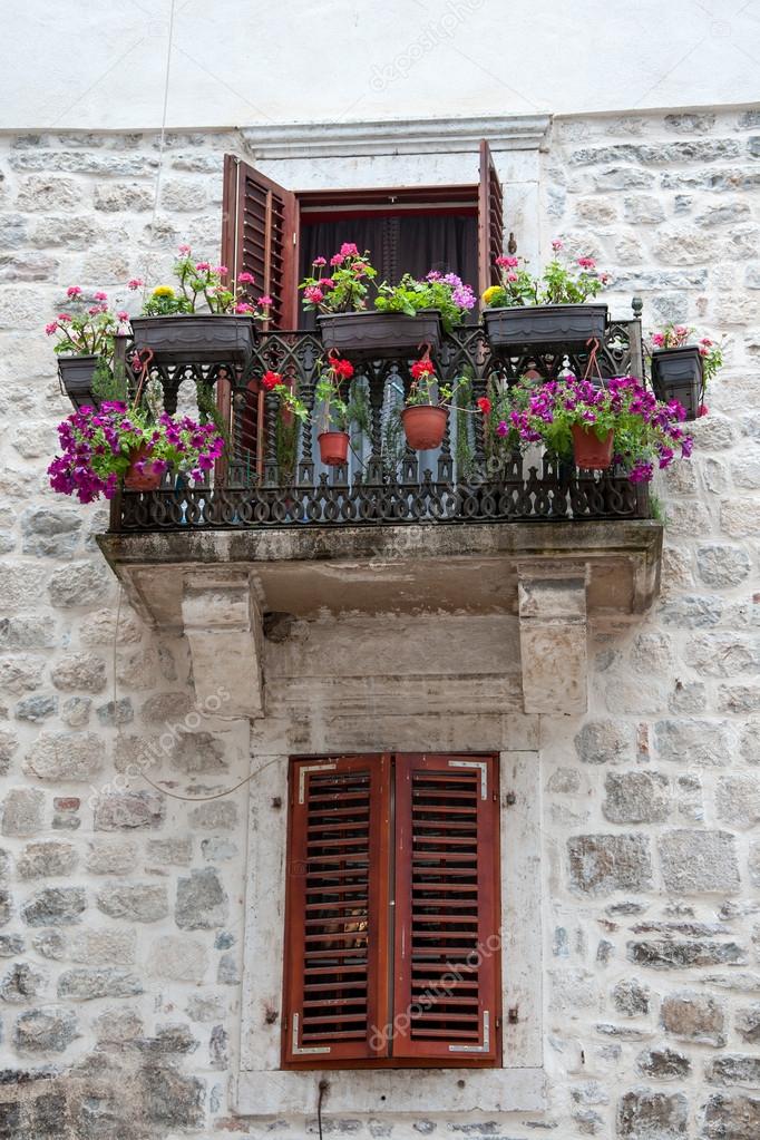 Old balcony with flowers and window with shutters