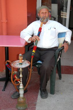 Yaşlı adamın bir nargile sigara içiyor.