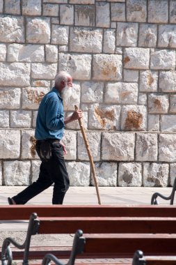 Older pilgrim goes around the church in Medjugorje