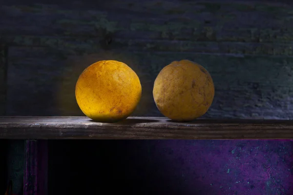 Two Flying Dragons Citrus Fruit on Shelf. First One Glowing.Dark But Colorful Background.