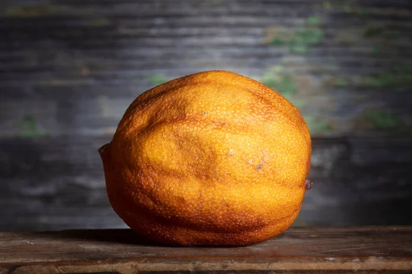 One Dried Lemon in Sharp Light on Wooden Background,  .Macro Shot. Minimal Still Life Photo