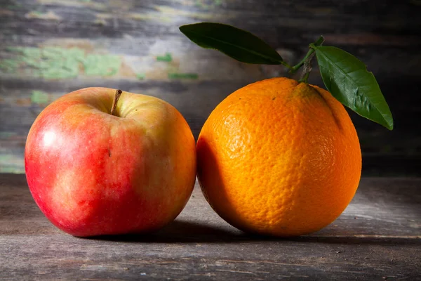 オレンジとアップルの秋の静物画 背景色の悪い木のテーブルの上のマクロ写真 スタジオでスポットライトで撮影 — ストック写真
