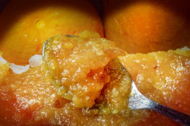 Kaşık Taze Portakal Reçelinde Boğuldu. Bir parça ekmeğin üzerine yayılın. Arkaplan Orange ve Jar 'ın Bir Parçası