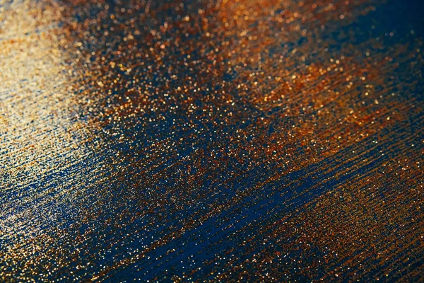 Koyu mavi bokeh üzerinde altın parıltısı soyut ışık odaklanmış arka plan.