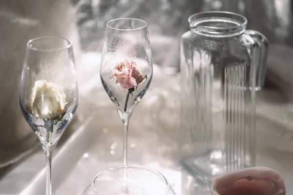 Sklenice a dvě prázdné sklenice se suchými růžemi na stole — Stock fotografie