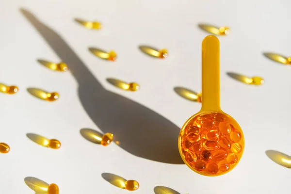 Yellow gel transparent gel capsules of vitamin d or omega 3 in spoon.