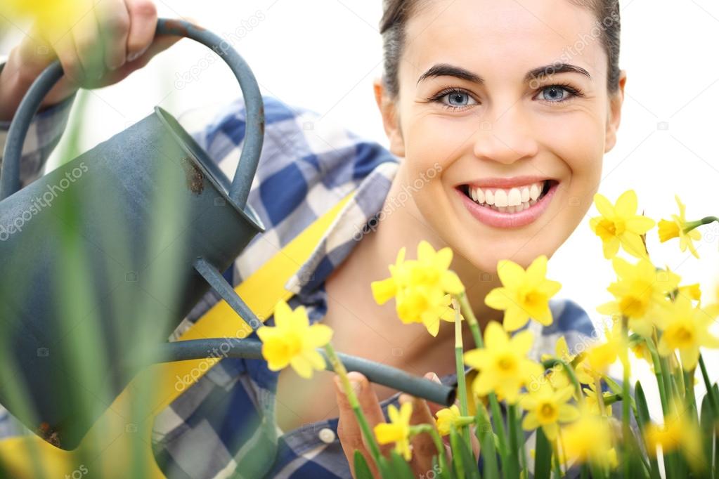 springtime, smiling woman in garden with watering can