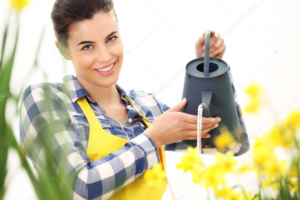 springtime, smiling woman in garden with watering can