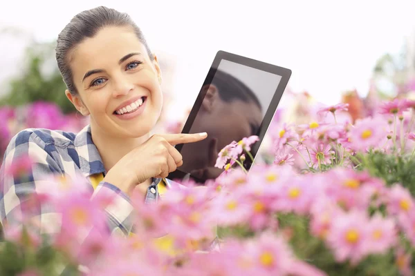 Springtime, woman with tablet smiling in garden flowers — Stock Photo, Image