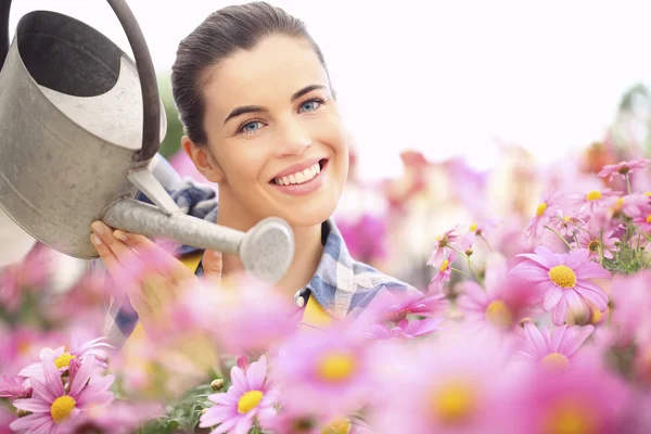Весна жінка посміхається в саду ромашок квіти з водою — стокове фото