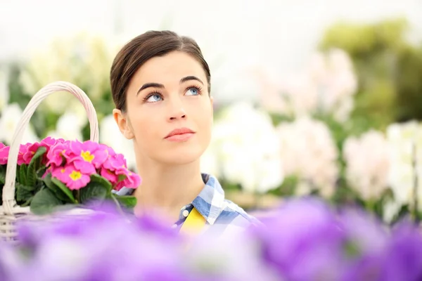 Mujer de primavera en el jardín mirando hacia arriba con flores de la cesta —  Fotos de Stock