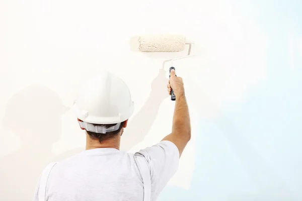 Pittore uomo al lavoro con un rullo di vernice, pittura murale concetto — Foto Stock