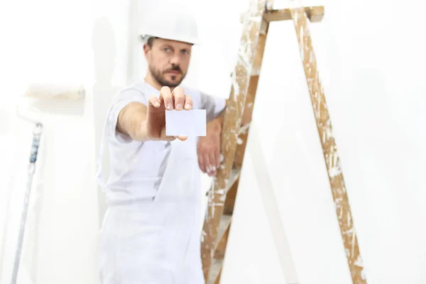 Målare man hand med visitkort, stege på vit vägg — Stockfoto