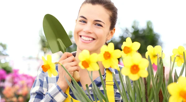 Frühling, lächelnde Frau im Garten kümmert sich um Blumen — Stockfoto