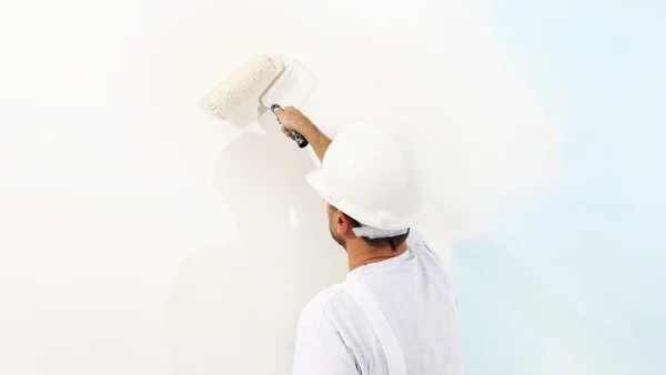 Pintor homem no trabalho com um rolo de pintura, conceito de pintura de parede — Fotografia de Stock