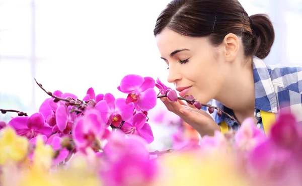 Mulher no jardim das flores, toca e cheira uma orquídea — Fotografia de Stock