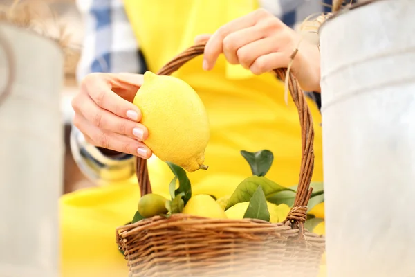Mão colher um limão e colocá-lo no vime cesta — Fotografia de Stock