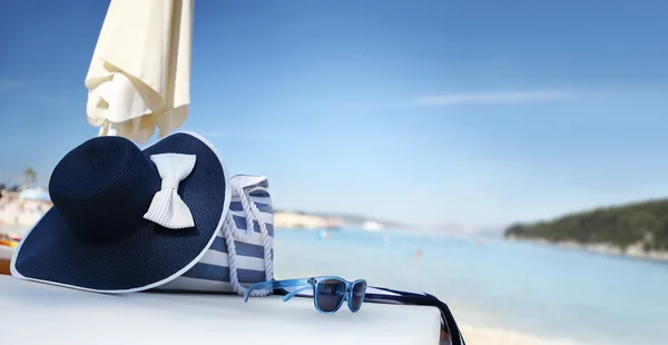 Chapeau sur la plage avec sac, lunettes de soleil et serviette — Photo