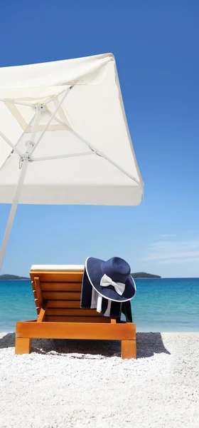 Parapluie et transat sur la plage avec chapeau bleu et serviette — Photo