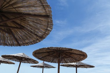 Gökyüzü arka plan üzerinde hasır plaj şemsiyesi