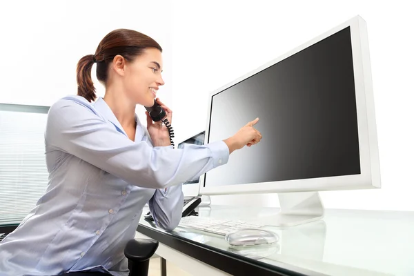 Mujer en el escritorio de la oficina hablando por teléfono apuntando el monitor —  Fotos de Stock