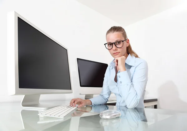 Женщина в офисе за столом перед экраном компьютера — стоковое фото