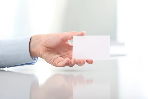 Hand hält leere Visitenkarte, auf dem Schreibtisch — Stockfoto