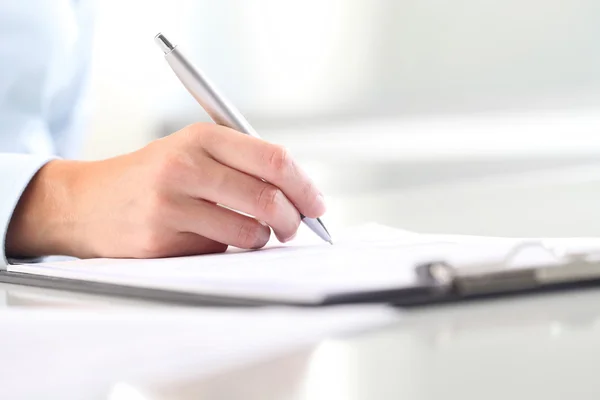 Mani di donna che scrivono su foglio di carta in un blocco a molla per appunti e una penna — Foto Stock