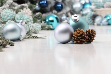 Mutlu noeller, gümüş ve mavi noel baloları ve kozalaklar beyaz masada, bir tebrik kartı şablonu gibi kullanışlı.