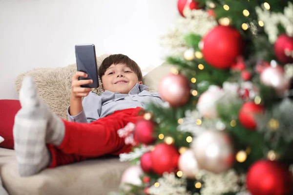 Wesołych Świąt Dziecko Domu Telefonem Komórkowym Pobliżu Oświetlonej Urządzonej Choinki — Zdjęcie stockowe