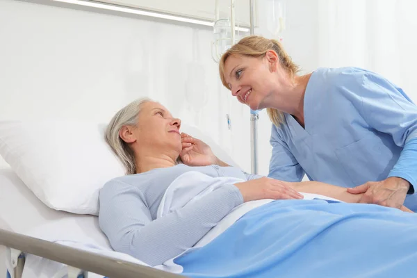 Enfermeira Sorrindo Reconforta Mulher Idosa Deitada Cama Quarto Hospital Acariciando — Fotografia de Stock