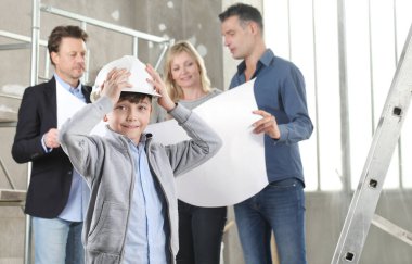 Mimar endişeli ve düşünceli bir çocuğu olan bir aileye ev tasarımı planları gösteriyor. Ev inşaatı hedef kavramı. Ev görünümü, iç dekorasyon ve ev dekorasyonu hakkında konuşmak için iç inşaat sahasında toplantı.