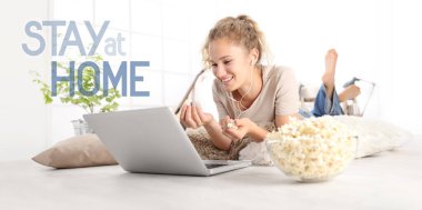 Genç kadın, beyaz zemin arka planında izole edilmiş evde mesajla, internetten film izliyor ve patlamış mısır yiyor. Coronavirüs önleme amaçlı sosyal medya kampanyasında kalıyor.