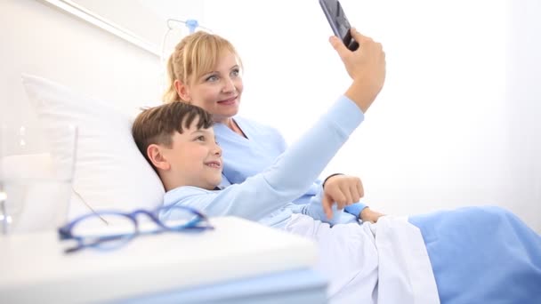 Hemşire Hastanede Yatan Cep Telefonuyla Selfie Çekerek Bir Çocuğa Bakıyor — Stok video