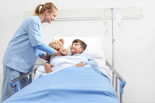 Smiling Nurse Giving Teddy Bear Happy Child Lying Bed Hospital — Stock Photo, Image