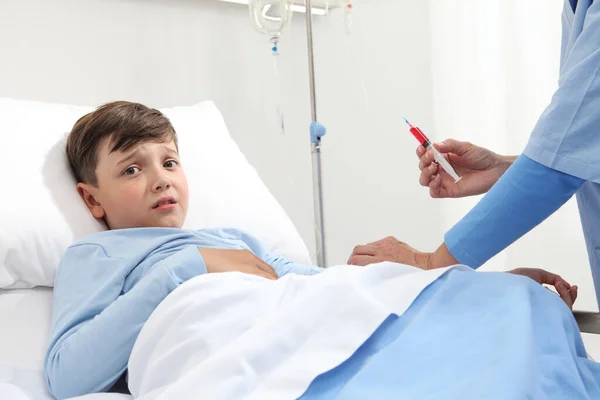 护士害怕孩子躺在病床上 看着被注射器针吓着的摄像机 进行了血液检测 — 图库照片