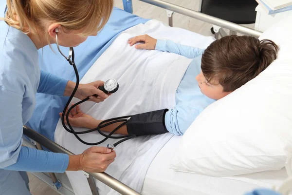 Dziecko Leżące Łóżku Pokoju Szpitalnym Pielęgniarka Mierząca Jego Ciśnienie Sfigmomanometrem — Zdjęcie stockowe